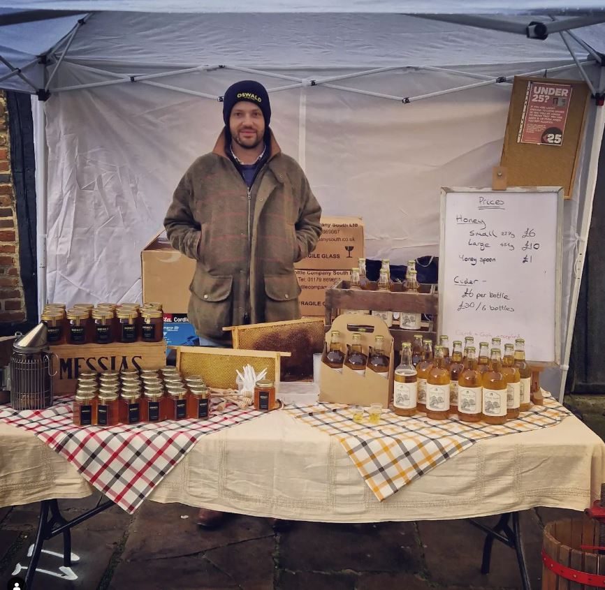 Honey, cider and a frame of honeycomb on the market stall